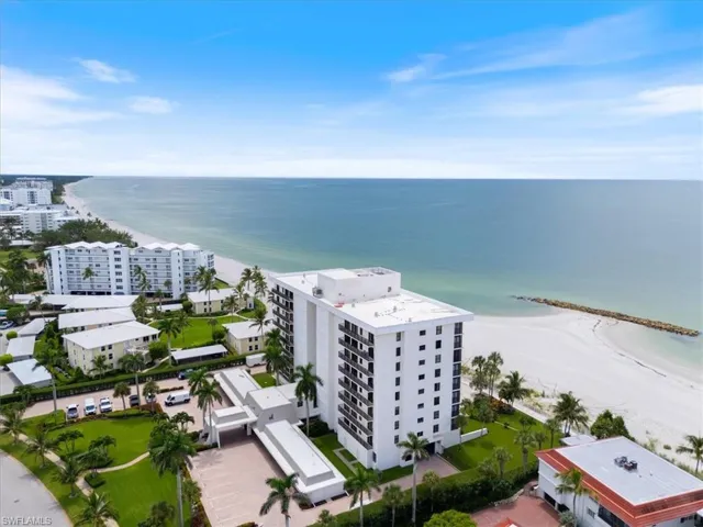 Bird's eye view of apartment complex and waterfront with a beach