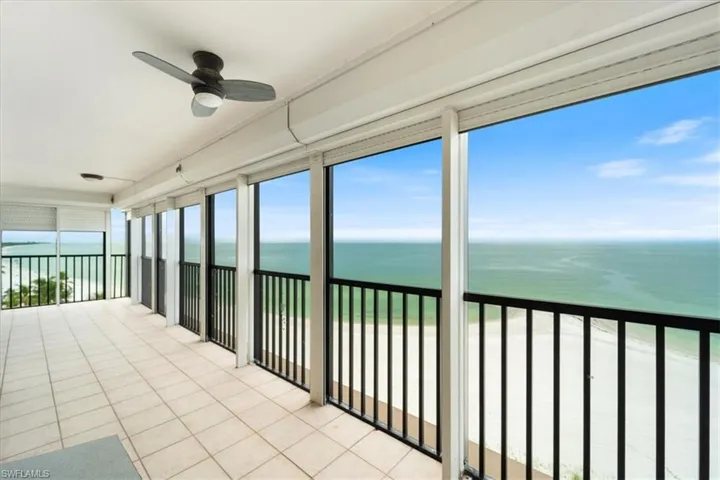 Unfurnished sunroom featuring view of water and beach and tile patterned flooring