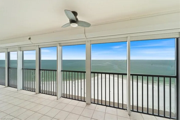 Unfurnished sunroom featuring view of water and beach and tile patterned flooring