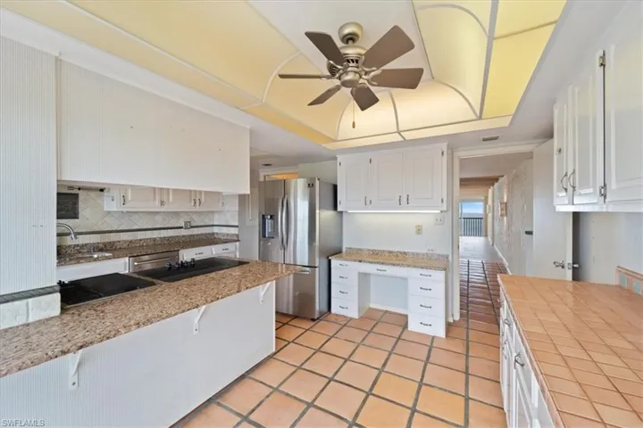 Kitchen featuring appliances with stainless steel finishes, white cabinetry, a breakfast bar area, tasteful backsplash, and light tile patterned flooring