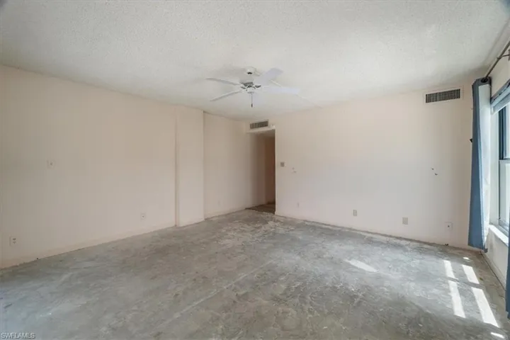 Unfurnished room with healthy amount of natural light, a textured ceiling, a ceiling fan, and concrete floors