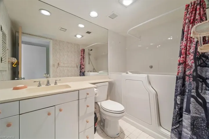 Bathroom with shower / bath combo with shower curtain, vanity, light tile patterned floors, and recessed lighting