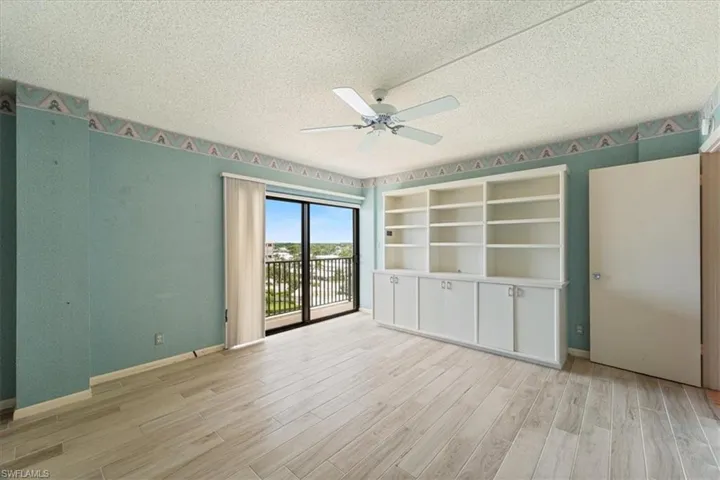 Empty room with ceiling fan, light wood finished floors, and a textured ceiling