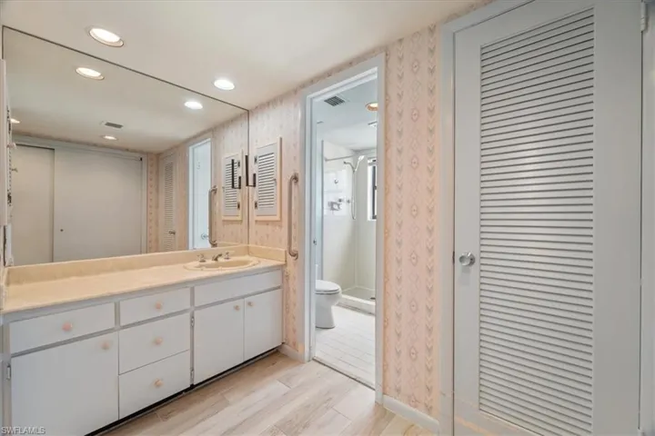 Full bathroom with a closet, a stall shower, vanity, wallpapered walls, and recessed lighting