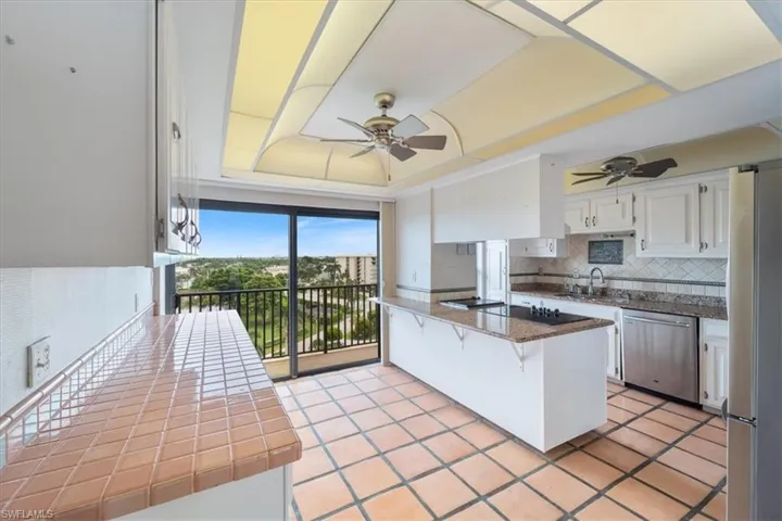 Kitchen featuring white cabinets, backsplash, appliances with stainless steel finishes, a breakfast bar, and light tile patterned flooring