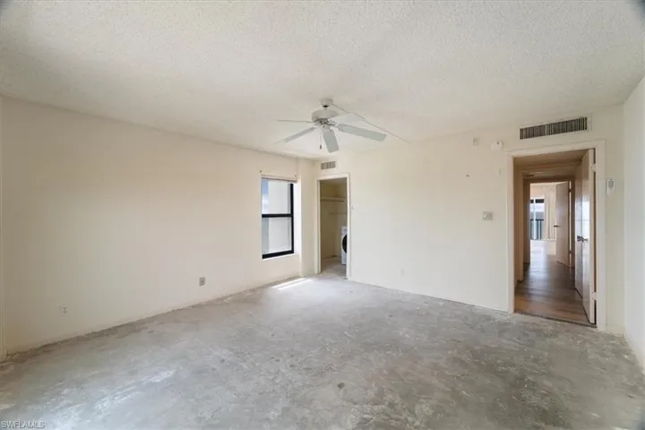 Empty room with a textured ceiling, a ceiling fan, and unfinished concrete floors