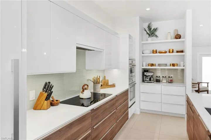 Kitchen featuring modern cabinets, white cabinetry, brown cabinets, open shelves, and tasteful backsplash