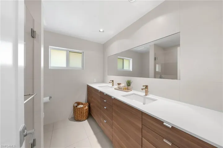 Bathroom with double vanity, light tile patterned floors, healthy amount of natural light, tile walls, and a stall shower