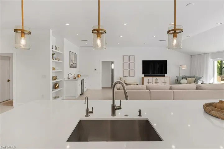 Kitchen featuring open floor plan, pendant lighting, recessed lighting, and light stone counters