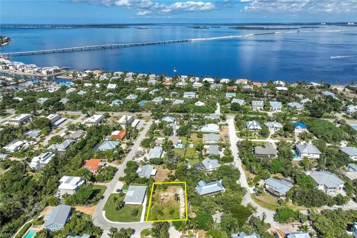 Aerial perspective of suburban area with a notable bridge, a large body of water, and property boundaries highlighted