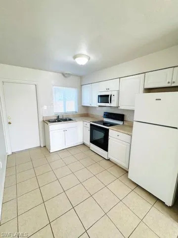 Kitchen featuring white cabinetry, tile flooring, a window, and a complete suite of appliances