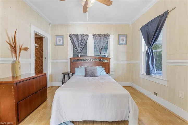 Bedroom featuring light hardwood / wood-style flooring, ceiling fan, and crown molding