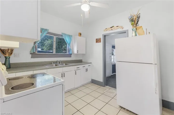 Kitchen with ceiling fan, white cabinetry, light tile patterned floors, sink, and white appliances