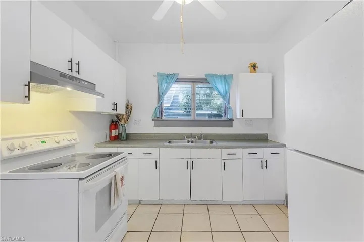 Kitchen with ceiling fan, white cabinetry, white appliances, and light tile patterned floors