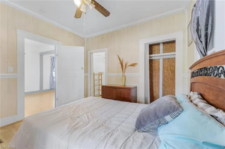 Bedroom with light hardwood / wood-style flooring, ceiling fan, ornamental molding, and a closet