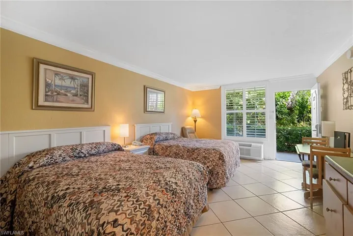 Tiled bedroom featuring access to outside, an AC wall unit, and crown molding