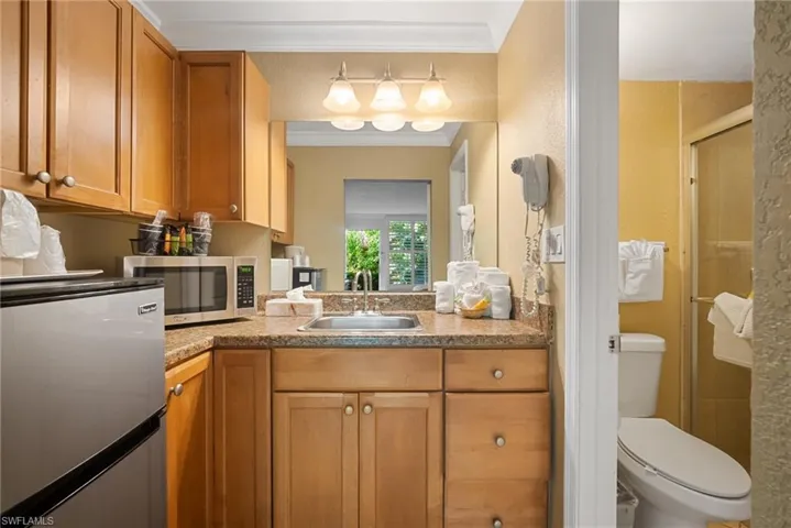 Bathroom with toilet, vanity, an enclosed shower, and ornamental molding