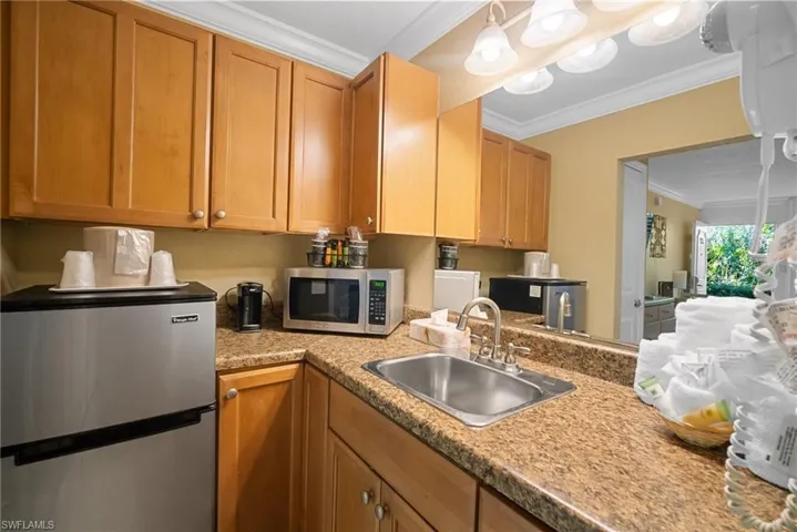 Kitchen featuring ornamental molding, sink, and appliances with stainless steel finishes