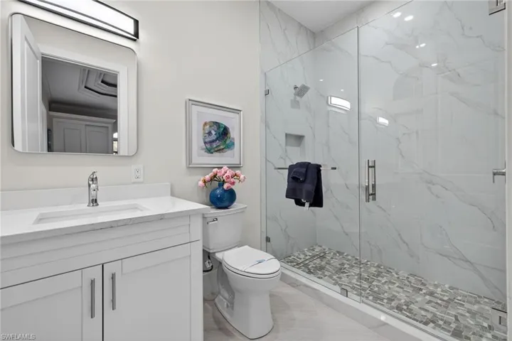 Bathroom featuring vanity and a marble finish shower