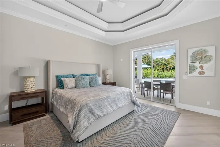 Bedroom featuring crown molding, access to outside, a ceiling fan, a raised ceiling, and light wood-style floors