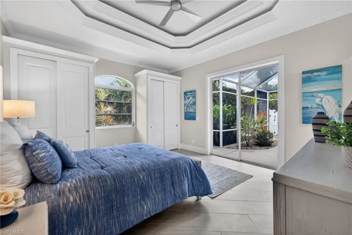 Bedroom featuring a sunroom, two closets, access to exterior, crown molding, and a raised ceiling