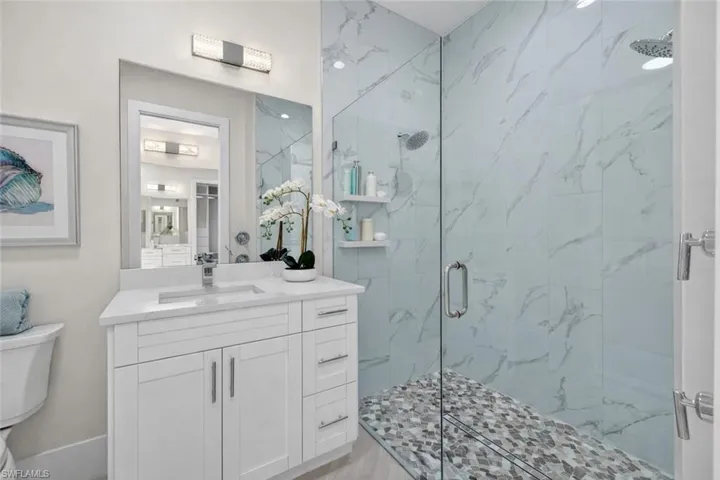 Bathroom featuring a marble finish shower and vanity