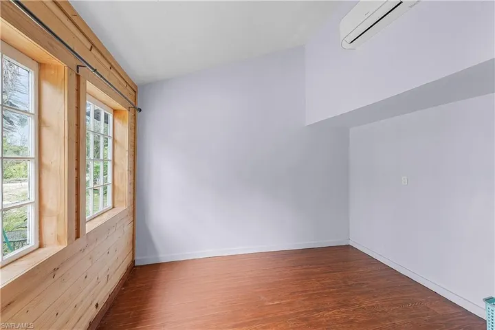 Spare room featuring plenty of natural light, dark hardwood / wood-style flooring, and a wall mounted AC