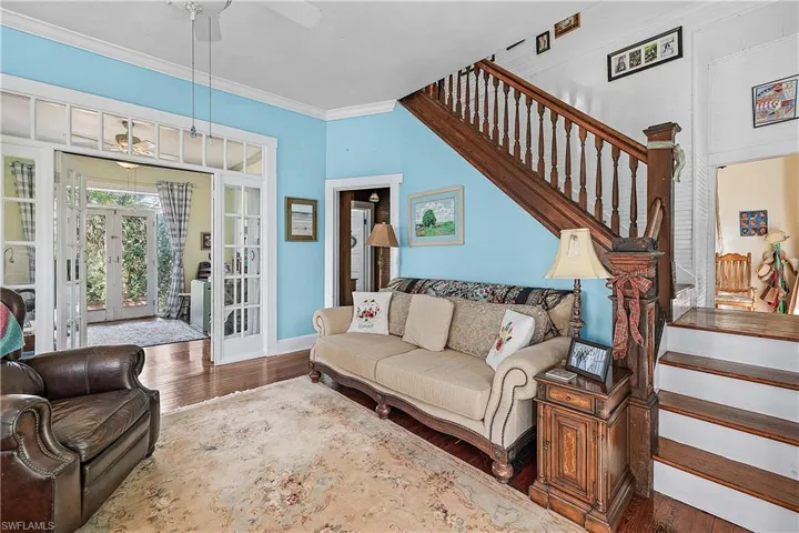 Living room with french doors, dark hardwood / wood-style floors, ceiling fan, and ornamental molding