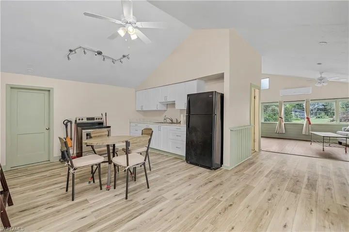 Dining space featuring light hardwood / wood-style floors, an AC wall unit, sink, and high vaulted ceiling