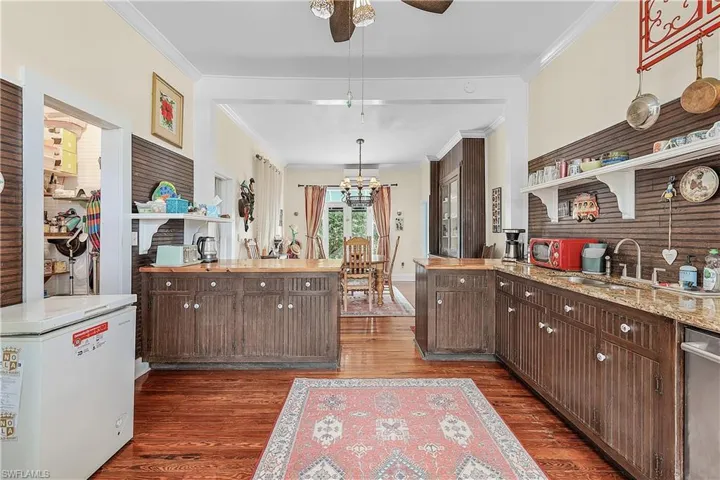 Kitchen featuring dark hardwood / wood-style flooring, refrigerator, ornamental molding, dark brown cabinetry, and dishwasher