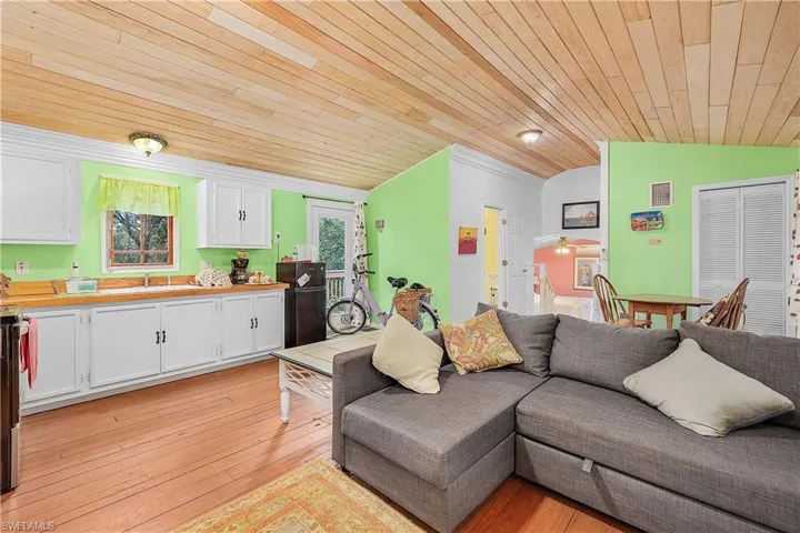 Living room featuring sink, light wood-type flooring, vaulted ceiling, and wood ceiling