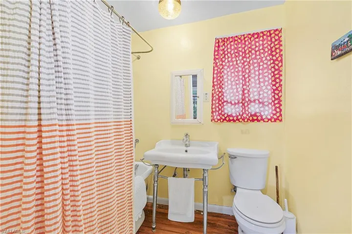 Bathroom with walk in shower, hardwood / wood-style floors, and toilet