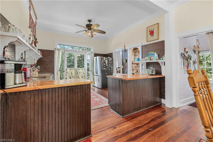 Kitchen with stainless steel refrigerator, a wealth of natural light, kitchen peninsula, and dark wood-type flooring