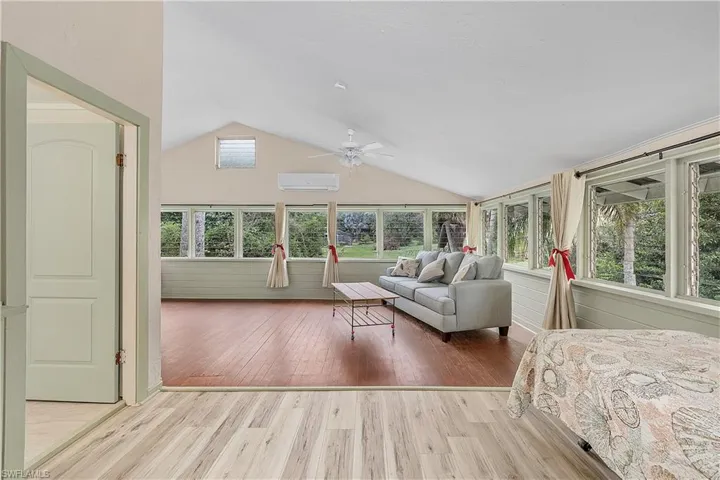 Unfurnished bedroom featuring lofted ceiling, ceiling fan, light hardwood / wood-style floors, and a wall mounted air conditioner
