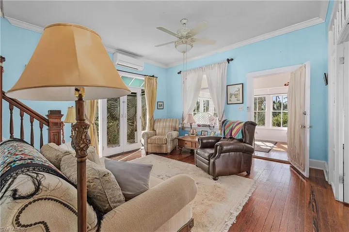 Living room with an AC wall unit, crown molding, ceiling fan, and dark wood-type flooring