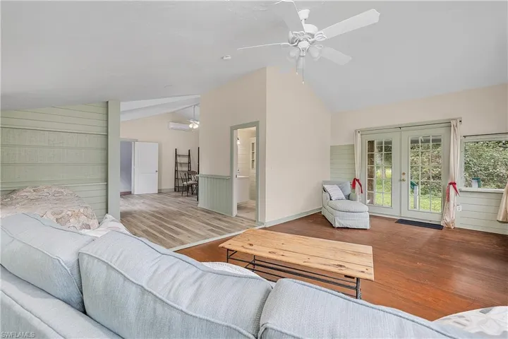 Living room featuring hardwood / wood-style flooring, french doors, wooden walls, and vaulted ceiling