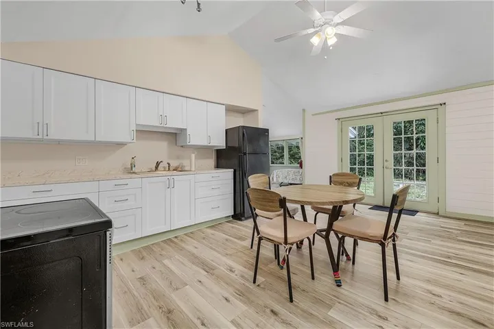 Kitchen featuring black fridge, sink, white cabinets, range, and light hardwood / wood-style floors