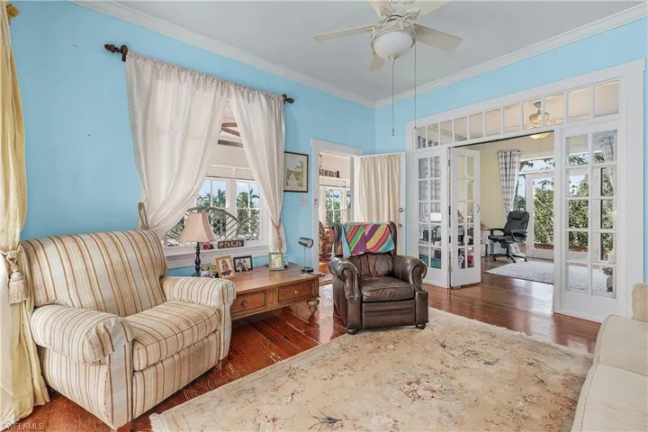 Living area with crown molding, french doors, ceiling fan, and dark wood-type flooring