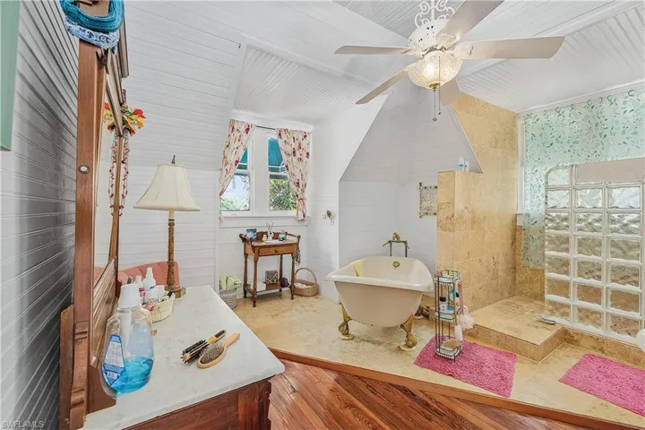 Bathroom with ceiling fan, plus walk in shower, lofted ceiling, and hardwood / wood-style flooring