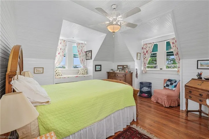Bedroom with multiple windows, ceiling fan, lofted ceiling, and hardwood / wood-style flooring