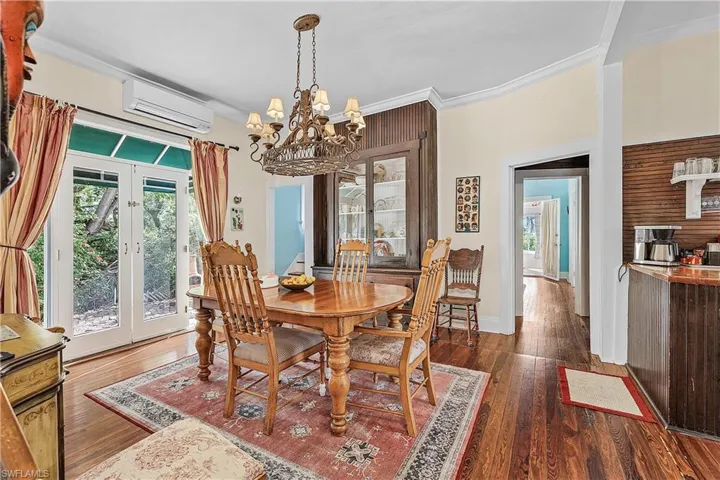 Dining room with french doors, crown molding, an AC wall unit, a notable chandelier, and dark hardwood / wood-style floors