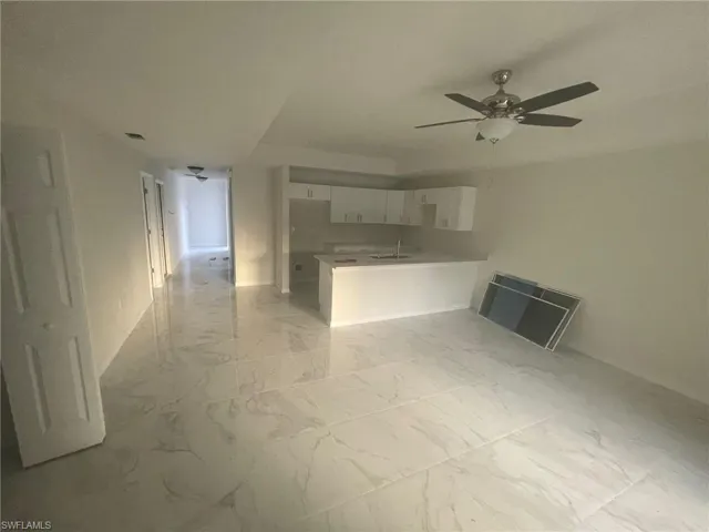 Unfurnished living room featuring sink, light tile patterned floors, and ceiling fan
