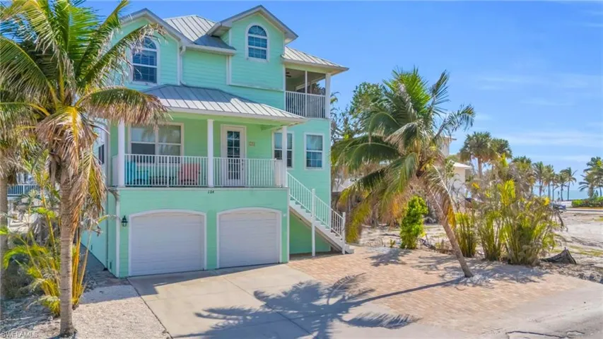 Coastal inspired home featuring a porch and a garage(Photo may be virtually enhanced)