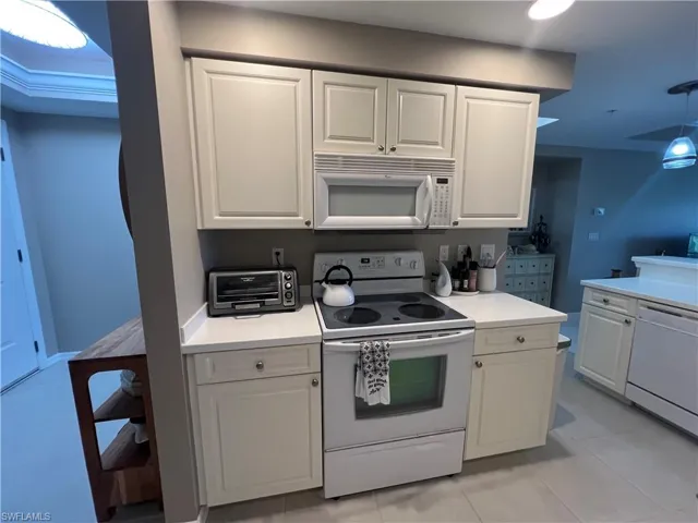 Kitchen with white appliances, white cabinetry, light countertops, and light tile patterned floors
