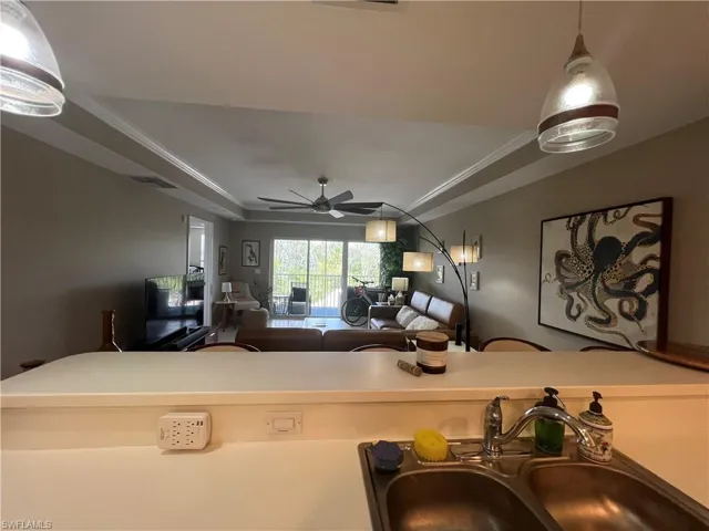 Living area with a raised ceiling, crown molding, and ceiling fan