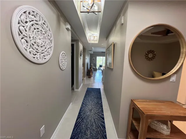 Hallway featuring light tile patterned floors, a chandelier, and crown molding