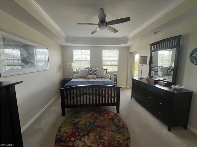 Bedroom with ornamental molding, a raised ceiling, light carpet, and ceiling fan