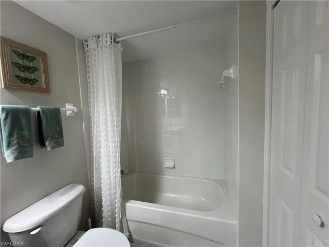 Bathroom featuring shower / bathtub combination with curtain and toilet