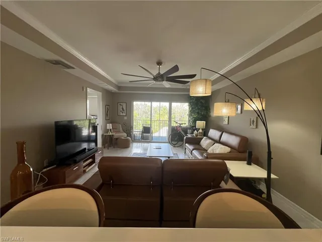 Living area with ornamental molding, a raised ceiling, and ceiling fan