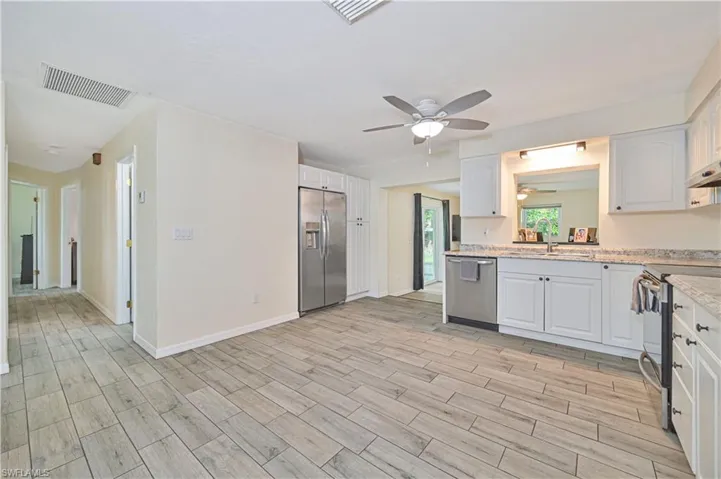 Kitchen featuring white cabinetry, light countertops, wood-finish flooring, stainless steel appliances, and a ceiling fan